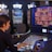 A person is seated at a slot machine console in a casino, focusing intently on the game displayed on the screen. The background shows several other illuminated gaming machines, adding a vibrant and colorful atmosphere to the scene.