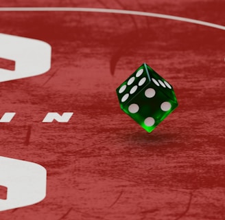 Two green dice with rounded edges are positioned on a red surface that seems to be part of a game board. The surface has white text and numbers on it, including the word 'LUCKYTOPSPIN' in capital letters.